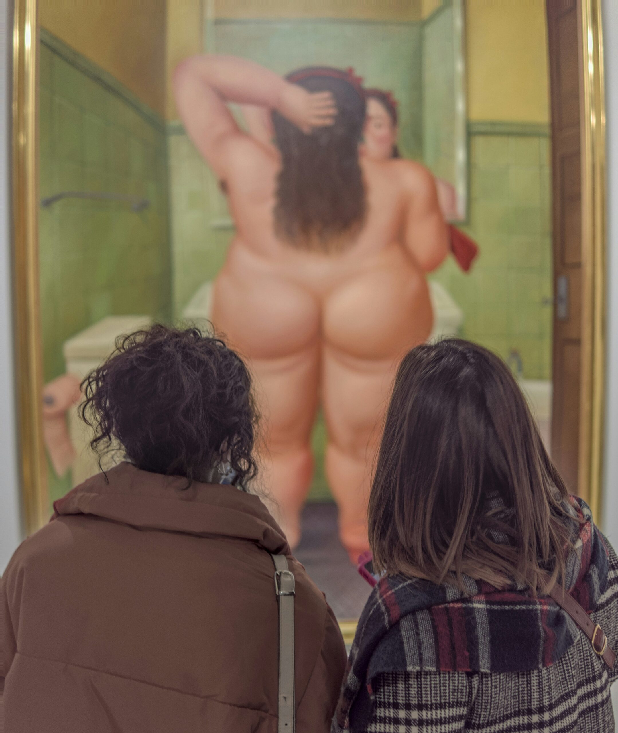 Twee museumbezoekers kijken naar het schilderij ‘El baño’ van Fernando Botero schaamte