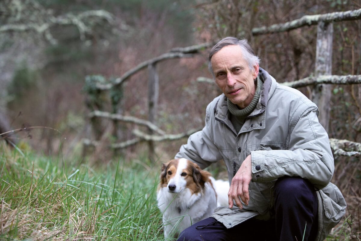 filosoof Ton Lemaire met zijn hond in de wei naast een hek