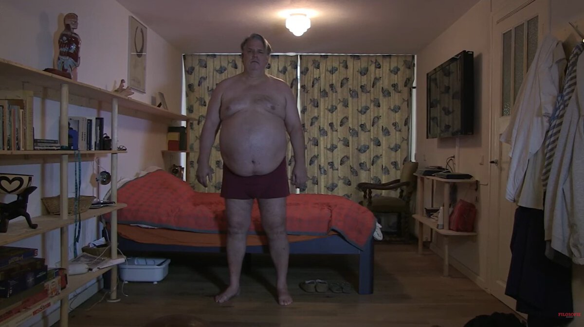 Een blote Jack Wouterse in een slaapkamer