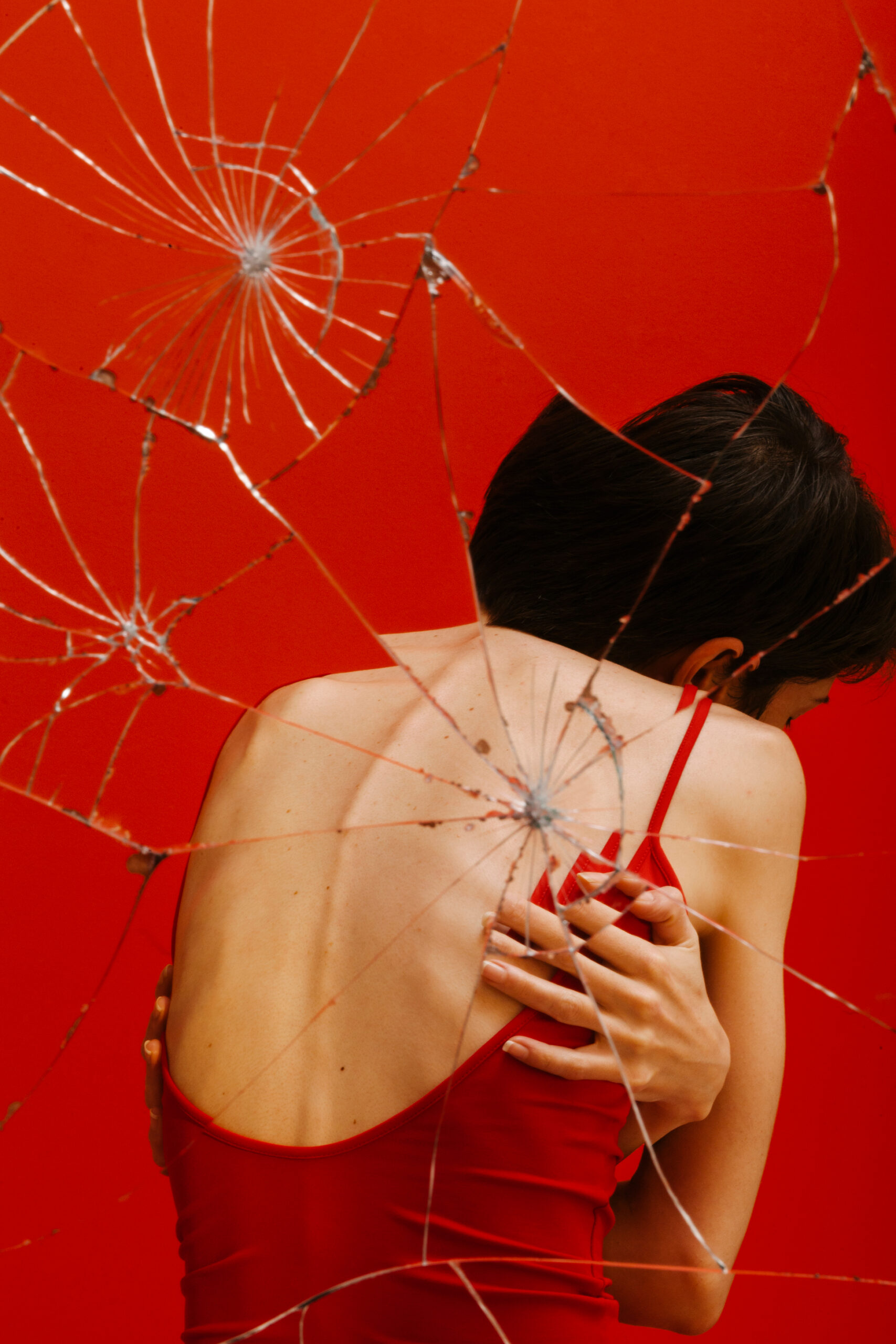 rug van een vrouw in een rode jurk voor een gebroken spiegel de mens