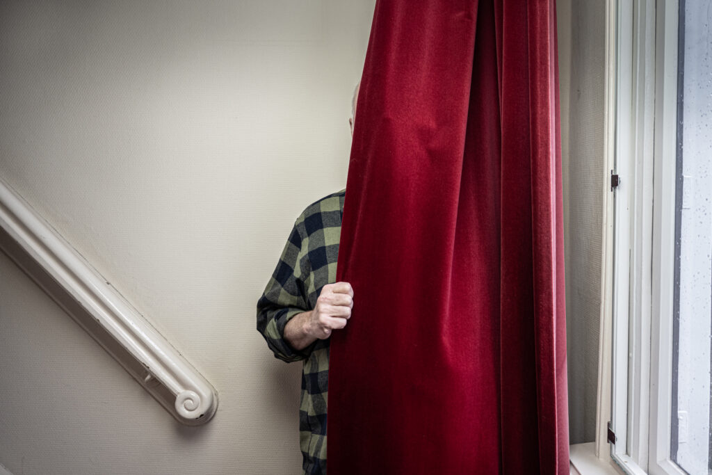 dichter Piet Gerbrandy verstopt achter een gordijn