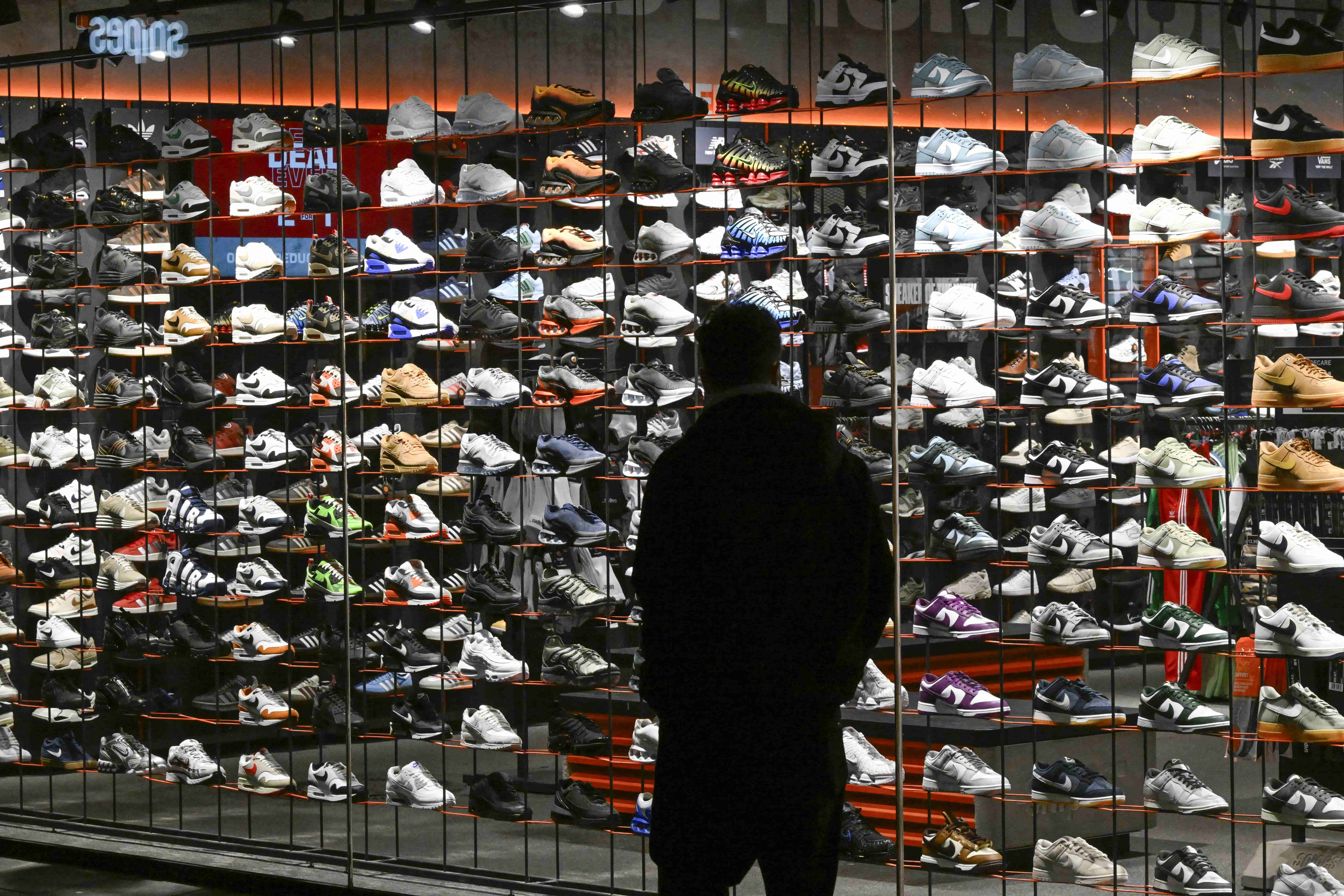 man staat voor een etalage vol sneakers twijfel